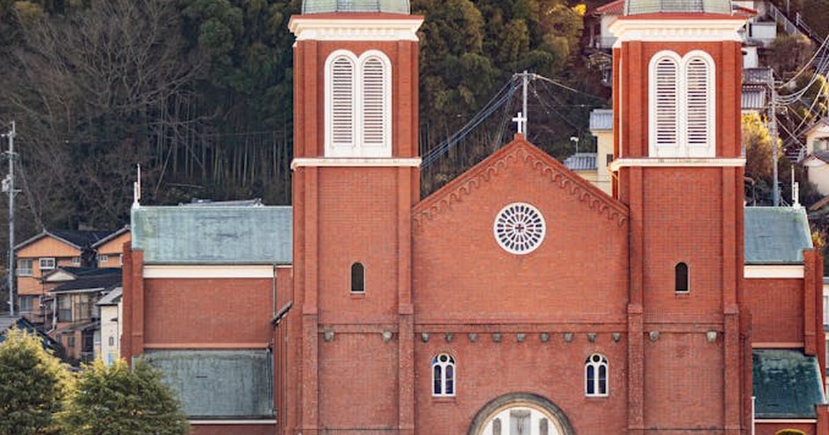 Stunning view of a Catholic church in Nagasaki, Japan, surrounded by lush greenery at sunset.