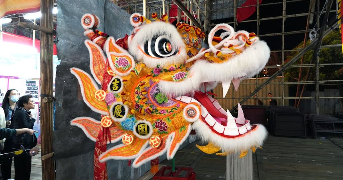Colorful lion dance costume displayed at a traditional festival in Hong Kong, illuminated against bamboo scaffolding.