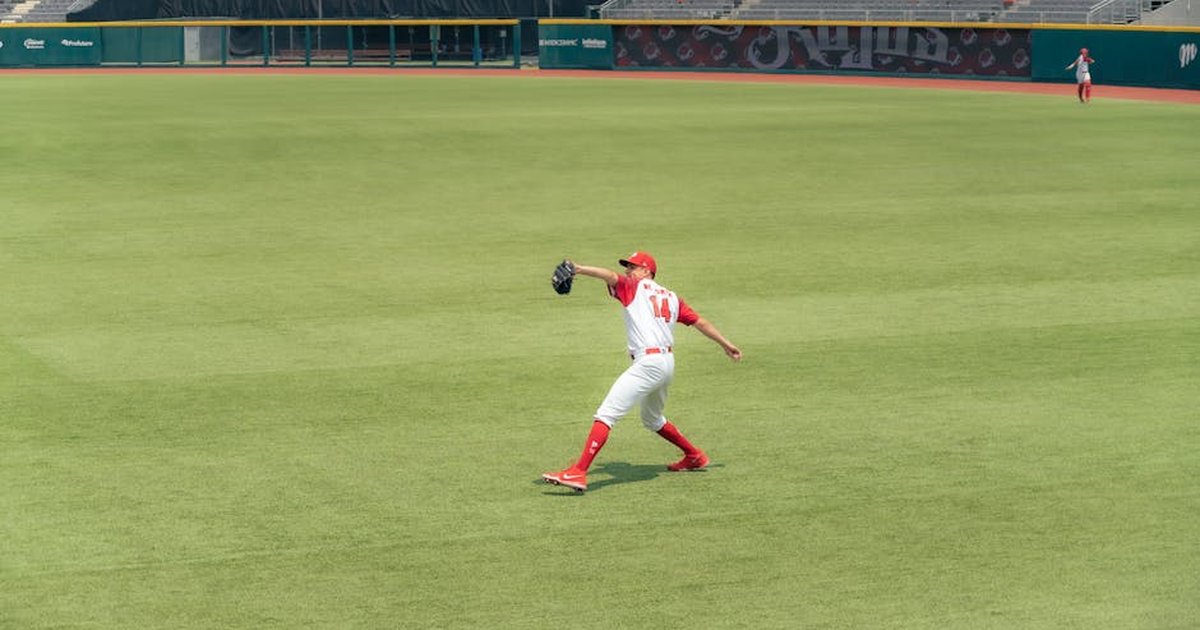 Athlete in action making a catch on green field in an empty stadium.