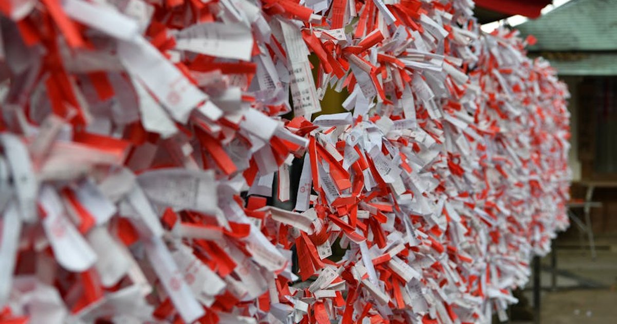 Colorful omikuji fortune papers tied at a Shinto shrine, symbolizing hopes and wishes.