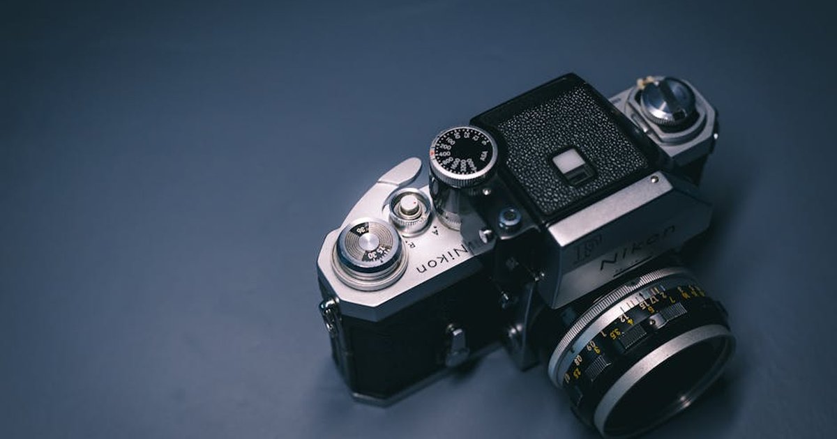 Detailed view of a classic Nikon film camera showcasing its mechanical features on a textured backdrop.