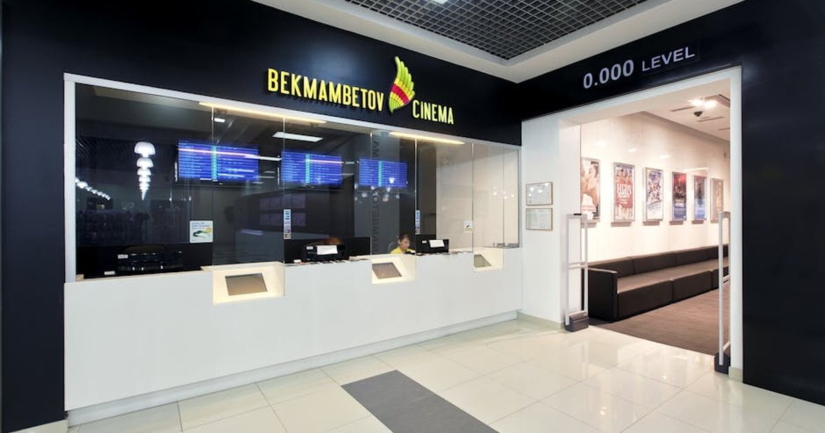 Interior view of a modern cinema box office with digital displays and sleek design, creating an inviting atmosphere.