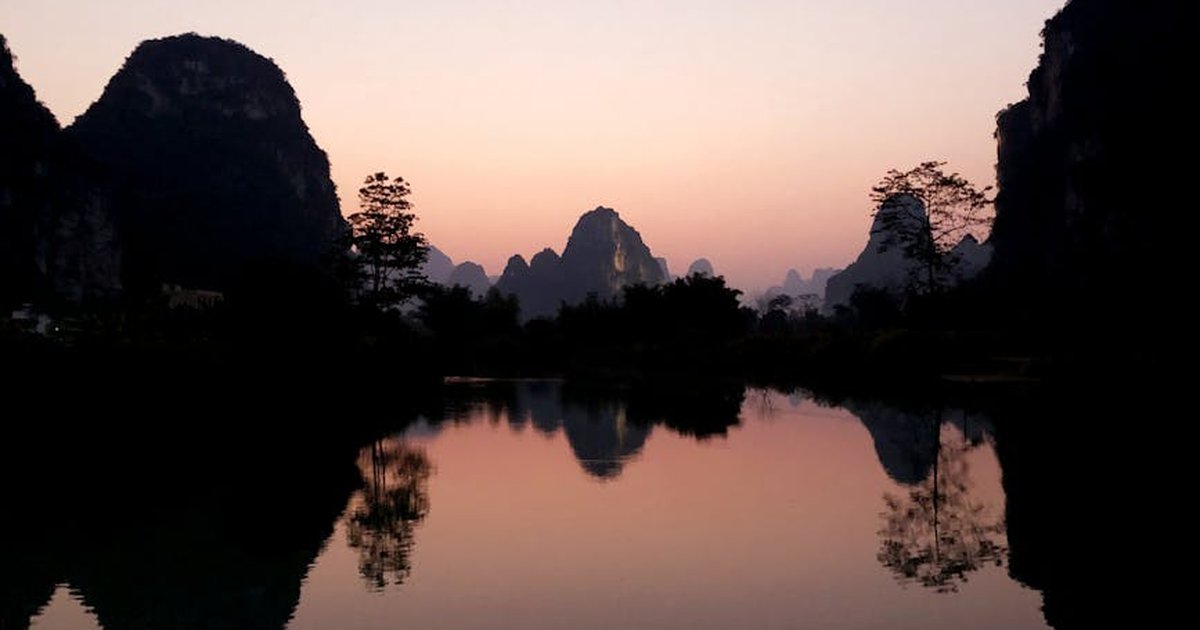 A peaceful sunset reflecting over a lake with karst mountains in Guangxi, China. Stunning natural beauty.