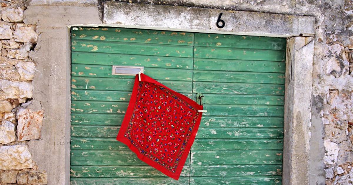 Charming green door with a red patterned cloth in a stone wall setting.