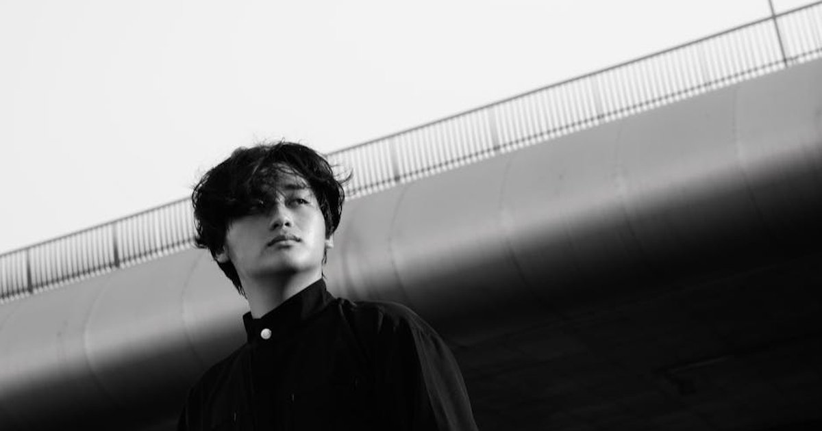A moody black and white portrait of a person under a bridge, conveying introspection.