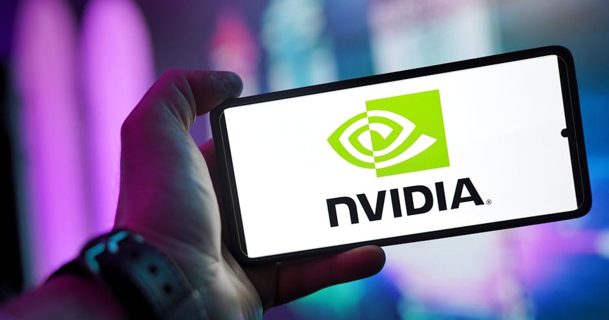 Close-up of a hand holding a smartphone showing the NVIDIA logo on screen with a blurred background.