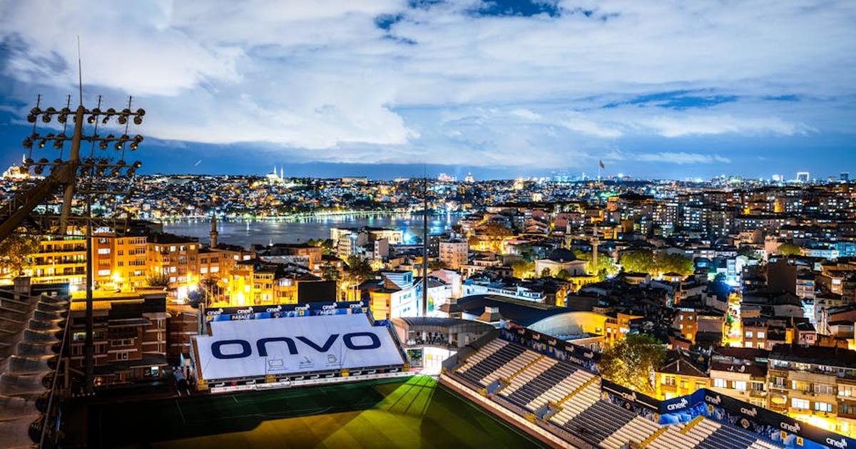 Aerial view of Istanbul's vibrant skyline at night with a focus on a well-lit stadium.