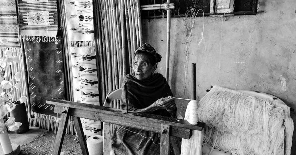 An elder artisan weaving carpets in a traditional workshop, Teotitlan del Valle, Mexico.