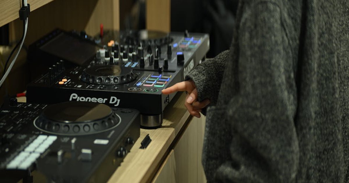 A DJ using a Pioneer mixer in a home studio setting in Seoul, showcasing modern electronic music mixing.
