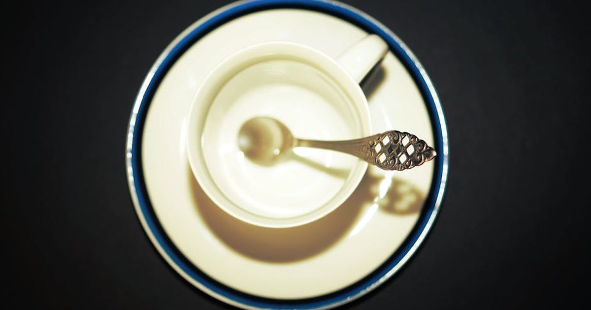 Top view of an empty porcelain tea cup with decorative spoon on saucer.