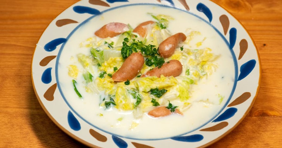 A savory Asian dish featuring sausages and leafy greens in a creamy sauce on an artisan plate.