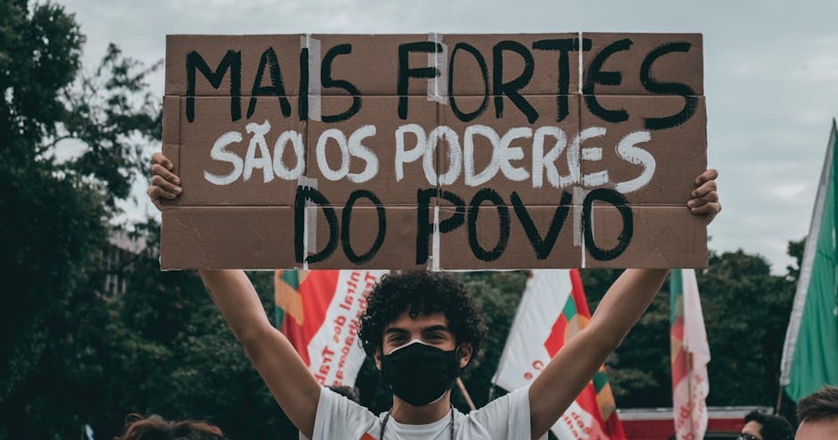 Protester in Rio holds sign saying 'Mais fortes são os poderes do povo.'