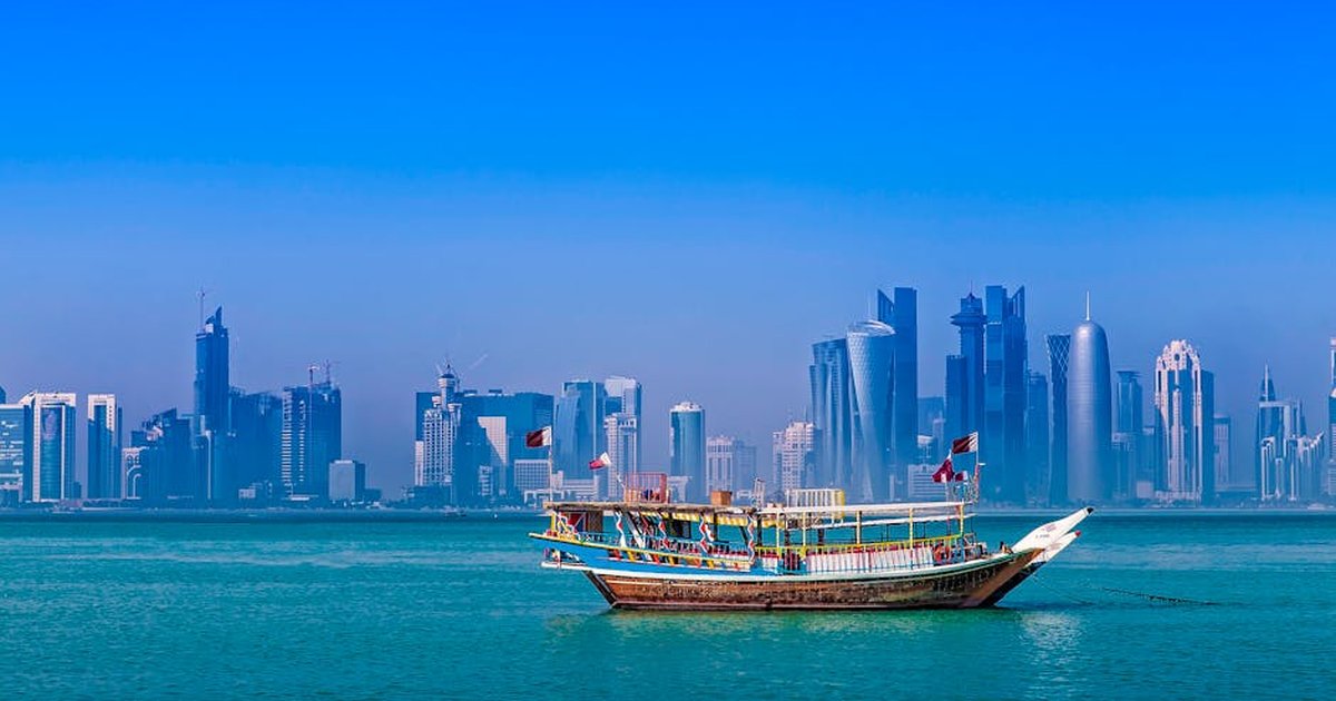 A traditional dhow boat against Doha's modern skyline over the Arabian Gulf.