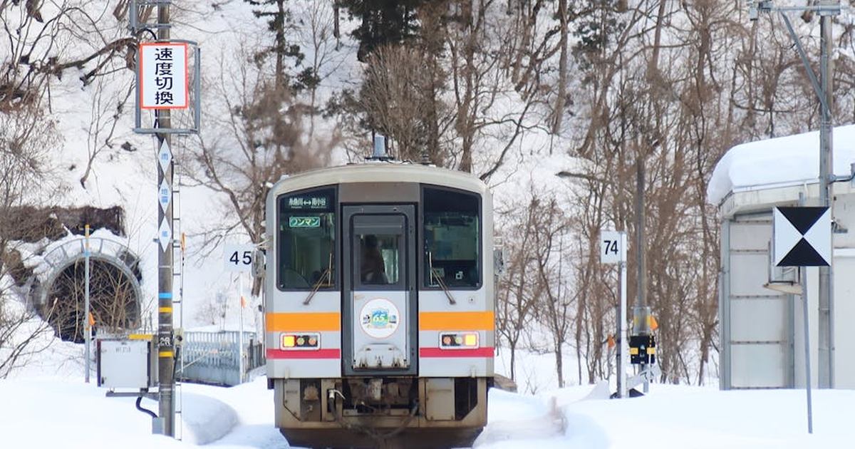 A train navigates snowy tracks in Otari Village, Nagano, Japan during winter.