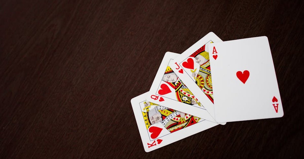 Elegant flat lay of playing cards featuring ace of hearts on a wooden surface.
