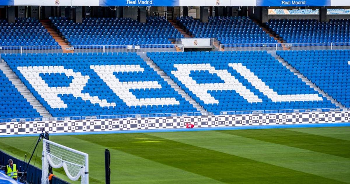Empty seating area in Real Madrid's stadium with 'REAL' prominently displayed in white.