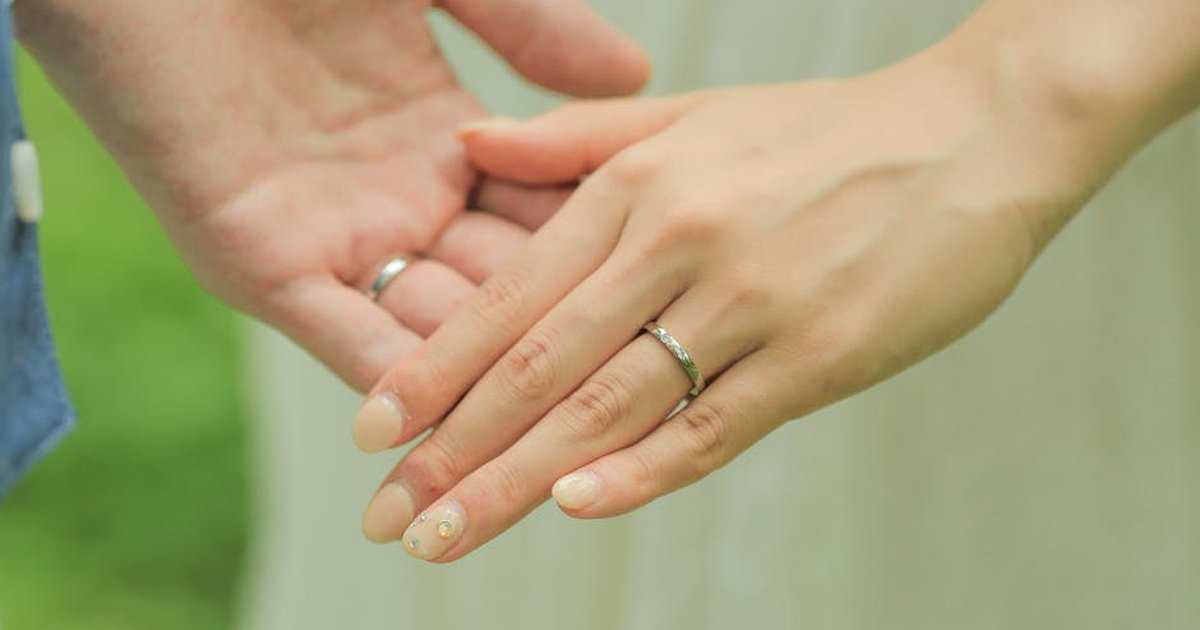 Close-up of newlywed couple's hands showcasing wedding rings in an intimate moment.