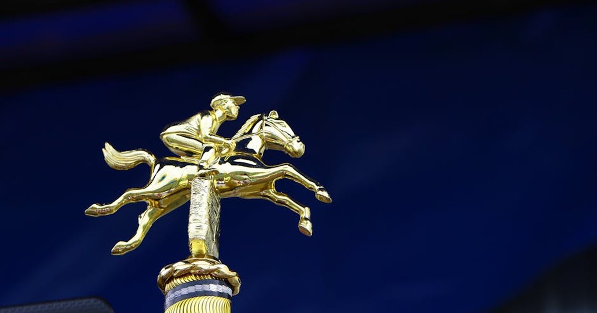 Close-up of a golden horse racing trophy with a rich blue background, symbolizing victory.