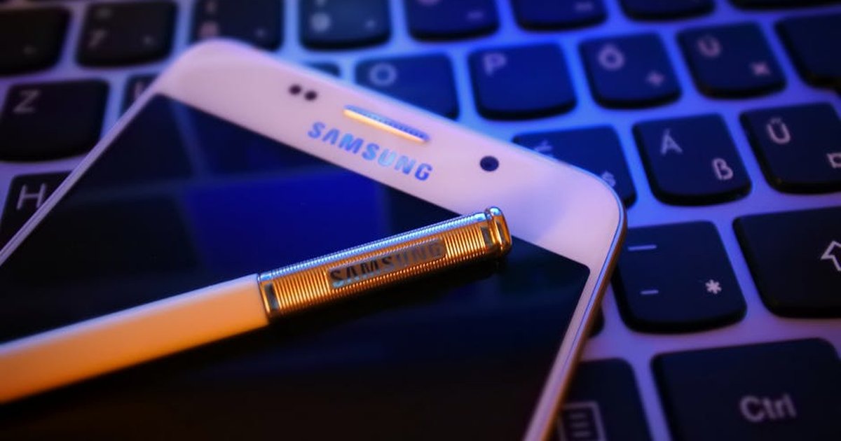 Close-up of a smartphone with a stylus on a keyboard, highlighting modern mobile technology.