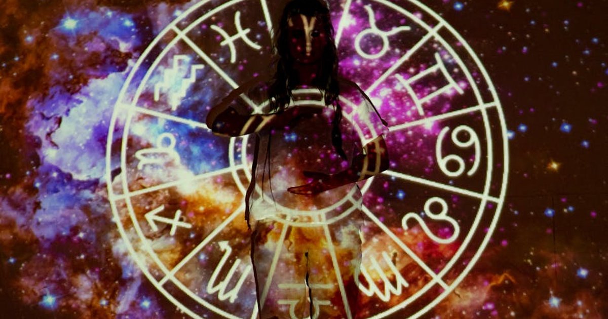 Woman standing with astrological symbols projected, evoking a mystical vibe.