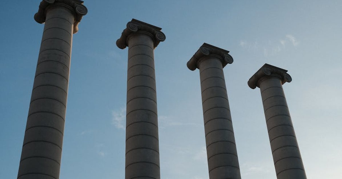 A low angle shot of Barcelona's iconic four columns under a clear blue sky, symbolizing Catalonian heritage.