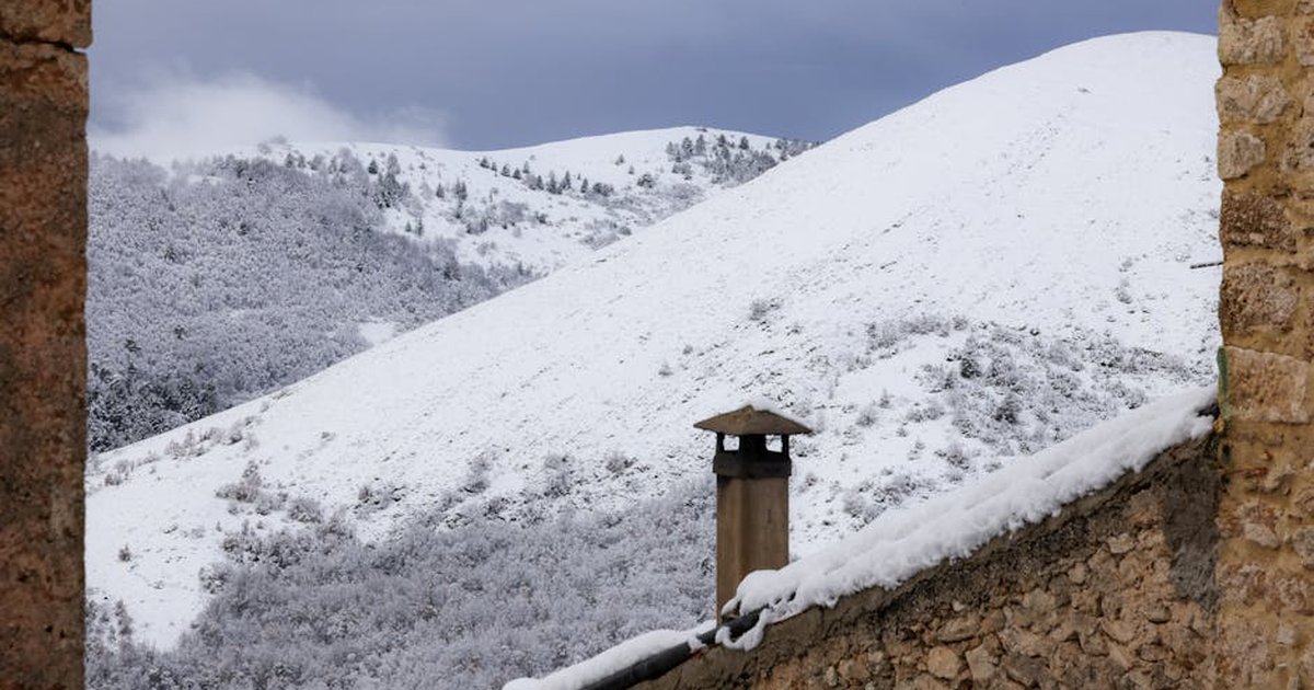 Charming winter scene of a snow-covered Italian village with mountain view.