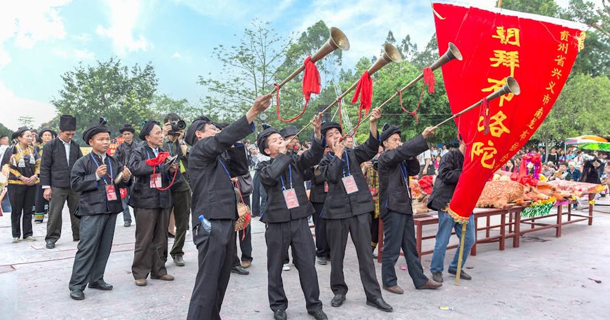 A vibrant street parade with musicians and banners during a traditional festival in Guangxi, China.