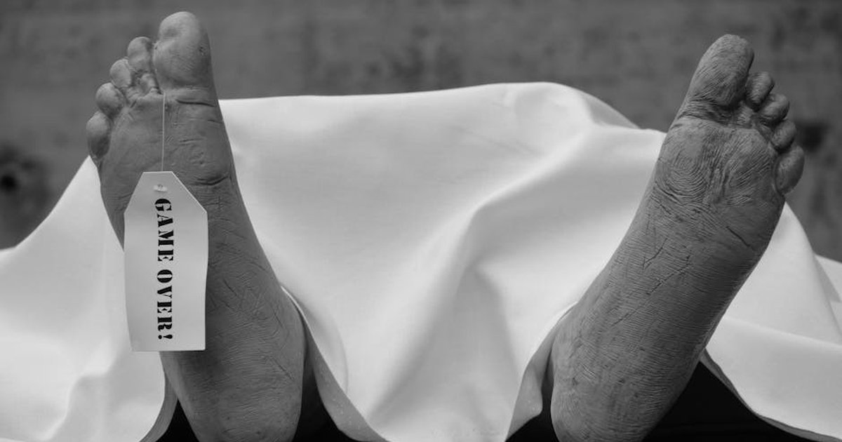 Conceptual black and white photo with symbolic 'Game Over' tag on feet.