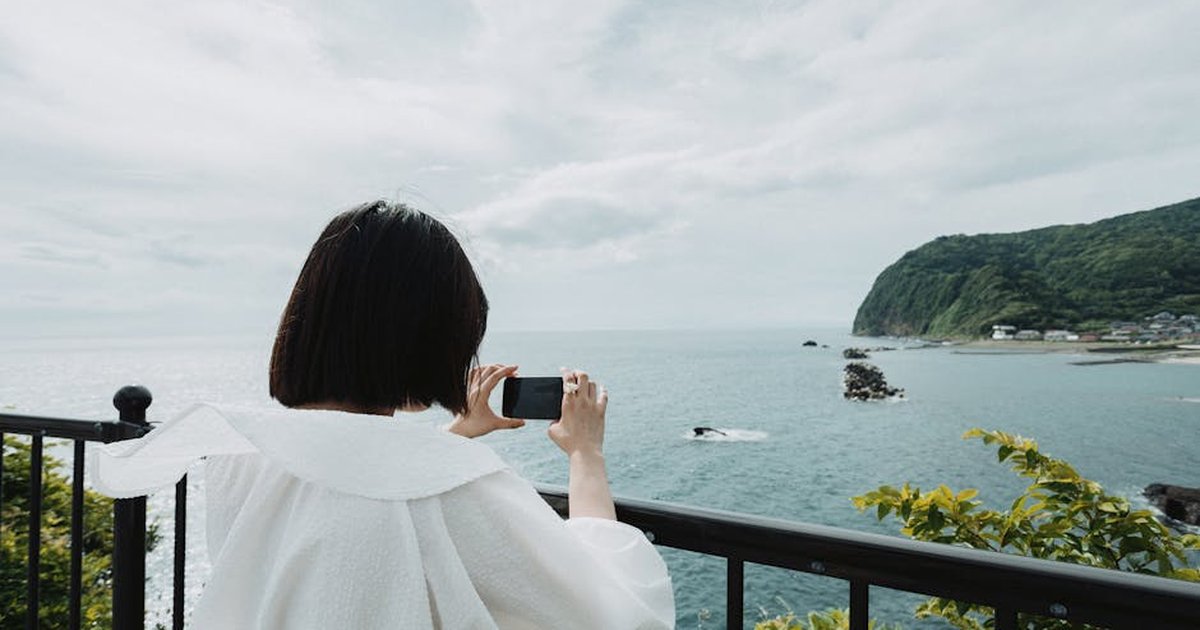 A woman in white captures the serene coastline of Nishiizu, Shizuoka, Japan.