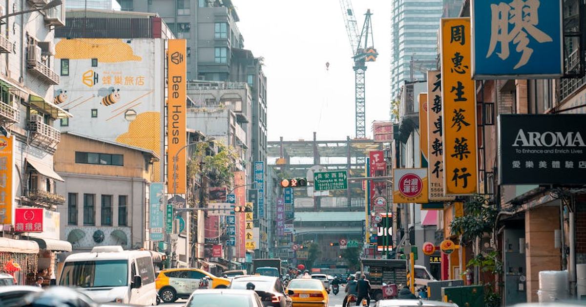 A lively urban street in Taipei, Taiwan, bustling with traffic and colorful signage.