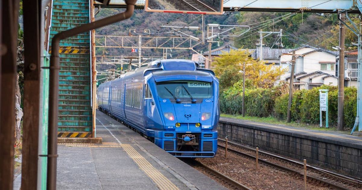 A blue train approaches a rustic station platform in Japan, showcasing public transportation infrastructure.