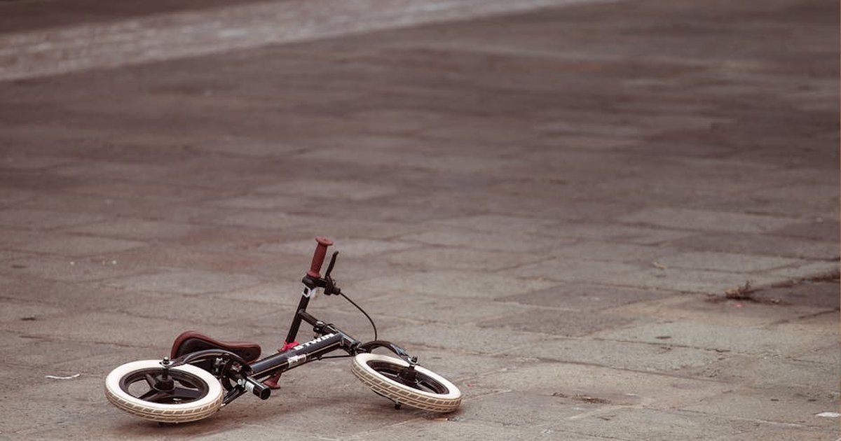 A small child's bike lies on an empty cobblestone street, evoking a sense of mystery and solitude.