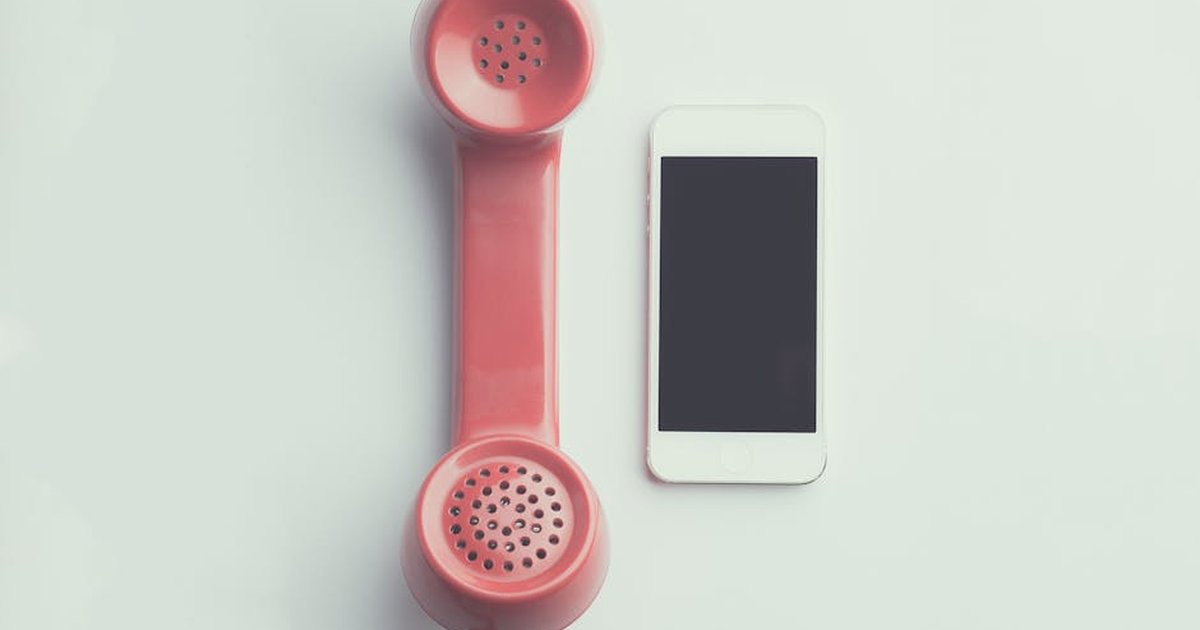 Comparison of a vintage pink telephone receiver and a modern smartphone on a simple backdrop.