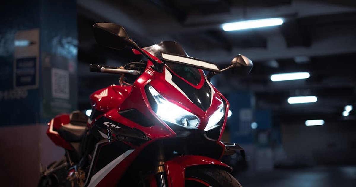 High-performance red sports motorcycle parked indoors with headlights on.