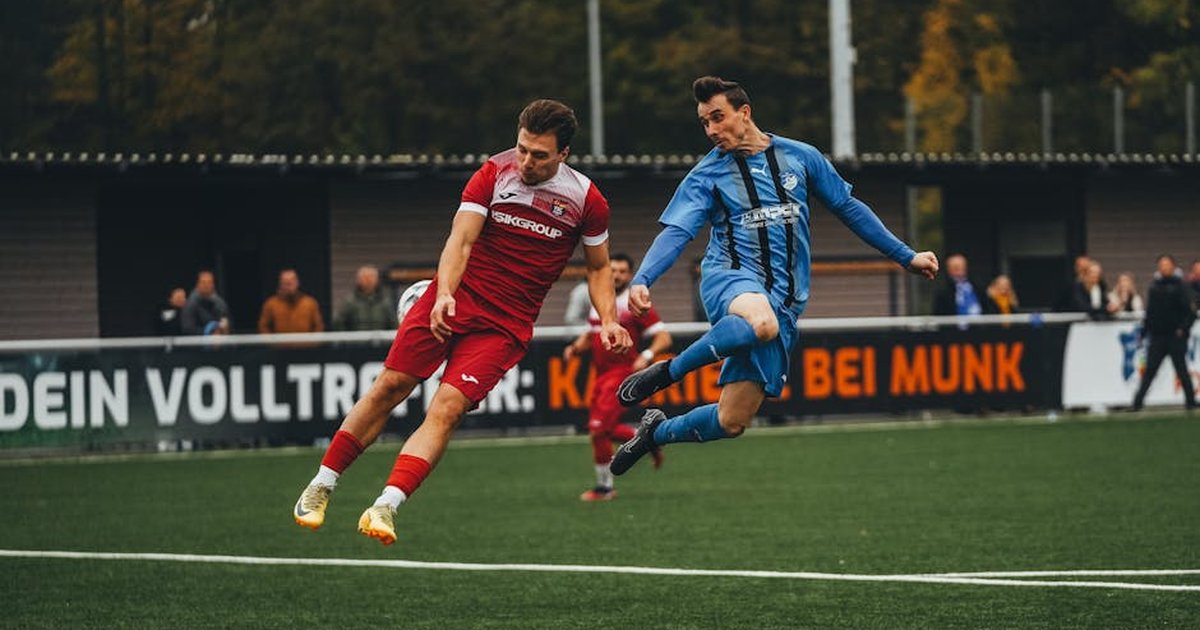 Two soccer players compete fiercely during a match on a green field.