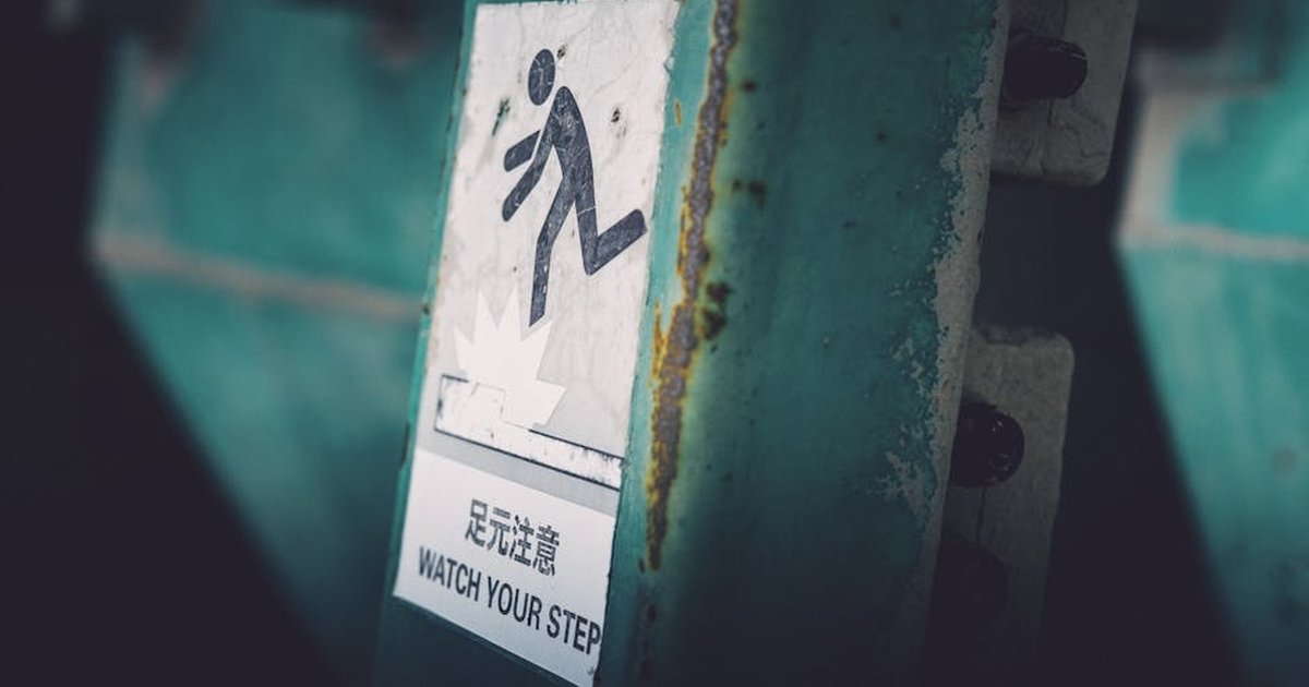 Dimly lit caution sign indicating 'Watch Your Step' in urban setting.