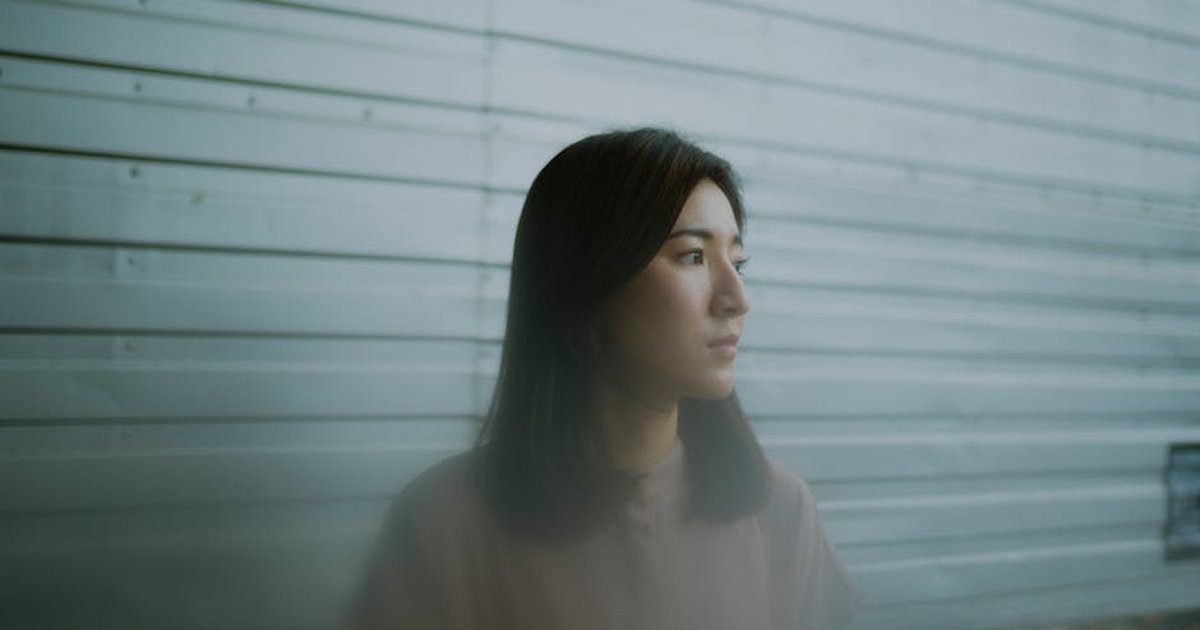 Thoughtful woman gazing outside, serene portrait with a soft focus.