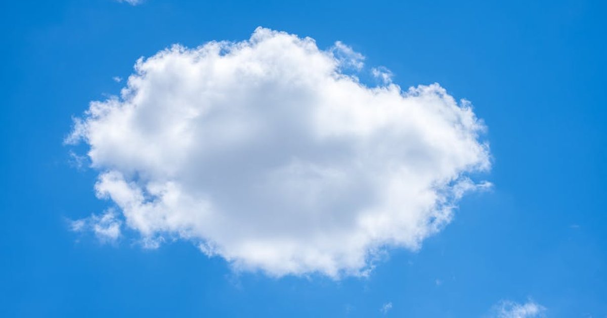 A single fluffy white cloud against a vibrant blue sky on a clear summer day.