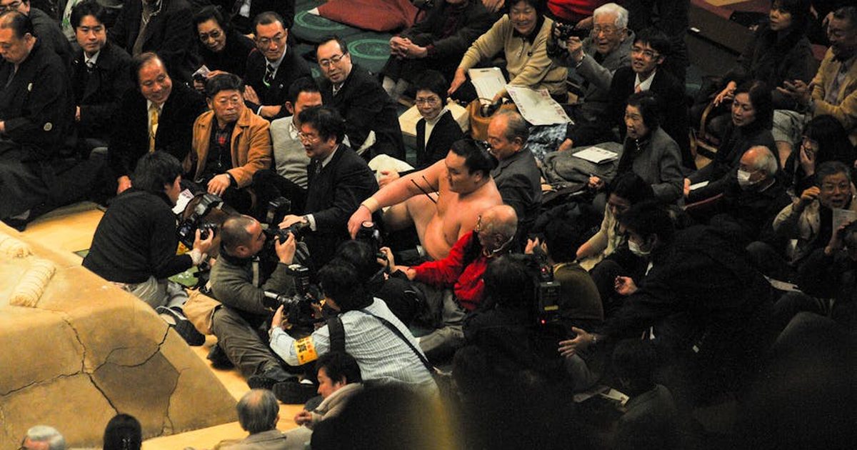 Sumo wrestling event with photographers capturing the scene, vibrant cultural moment.