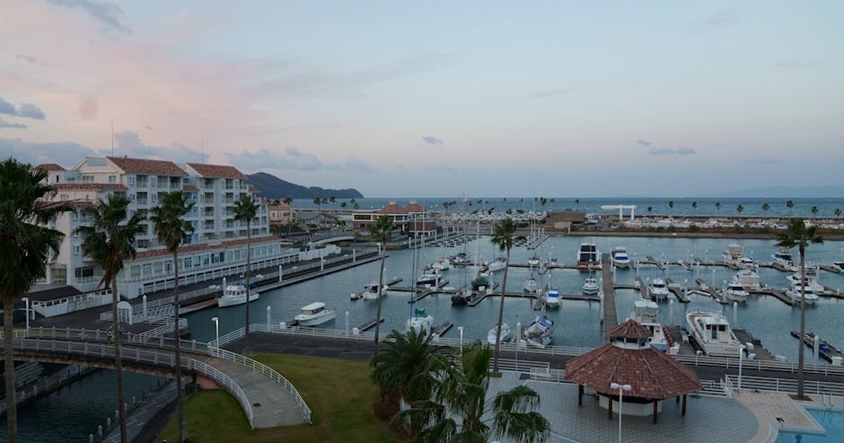 Aerial view of a serene marina with luxury yachts and coastal buildings in Japan during sunset.