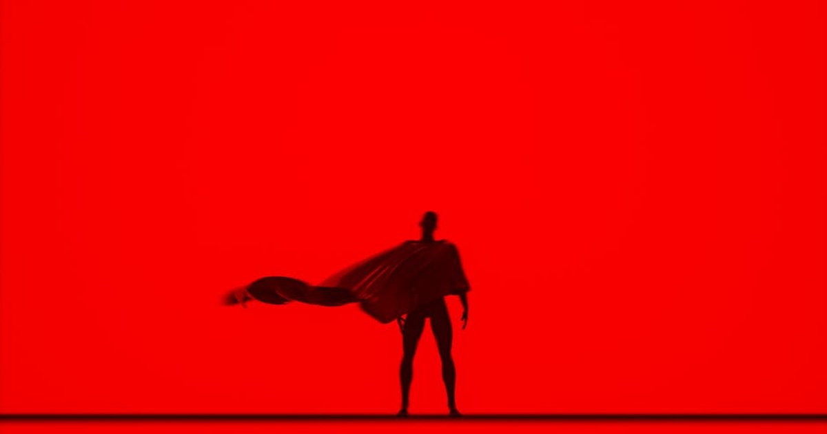 Artistic silhouette of a person with a flowing cape against a vivid red backdrop, creating a dramatic effect.