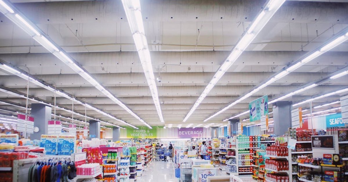 Interior of modern supermarket with various shelves with assorted colorful products under bright lamps