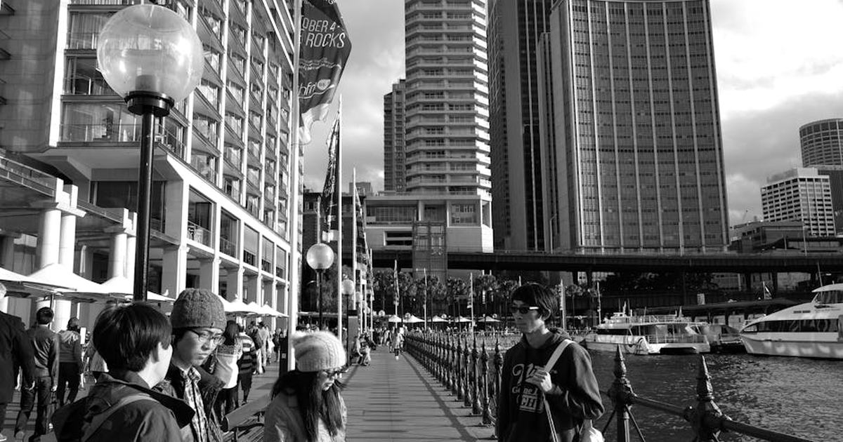Black and white street view in Sydney with pedestrians and skyscrapers on a sunny day.