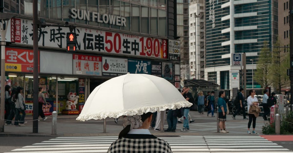 A stylish woman holding an umbrella crosses a bustling Tokyo street, showcasing urban life.