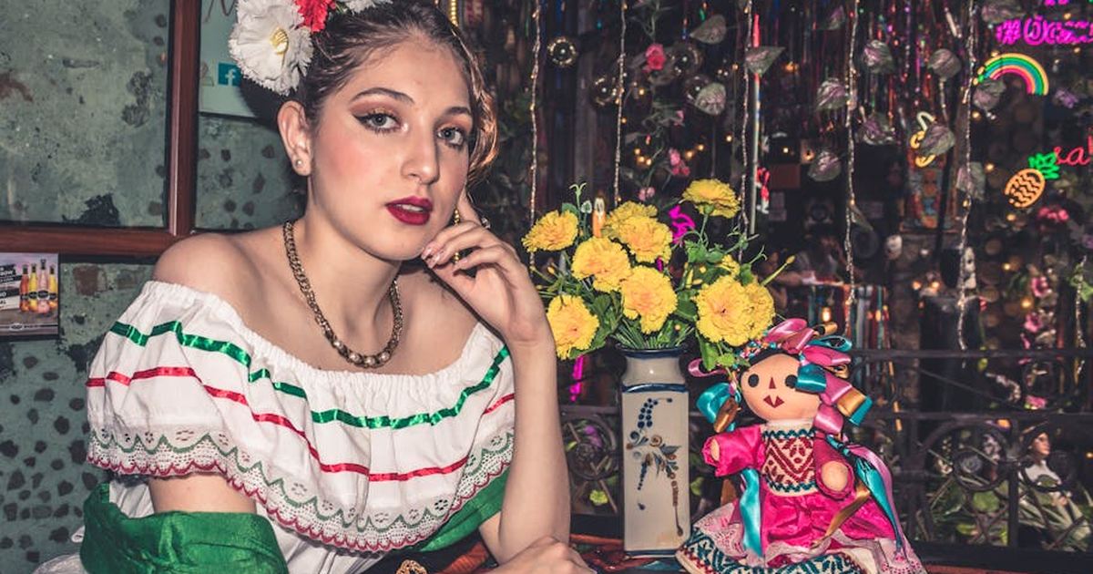 Young woman in traditional Mexican dress with vibrant colors and cultural decorations.