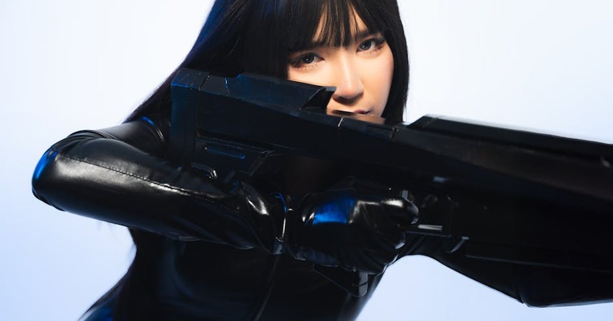 A person in sleek black cosplay attire holds a futuristic weapon, exuding a sci-fi vibe.