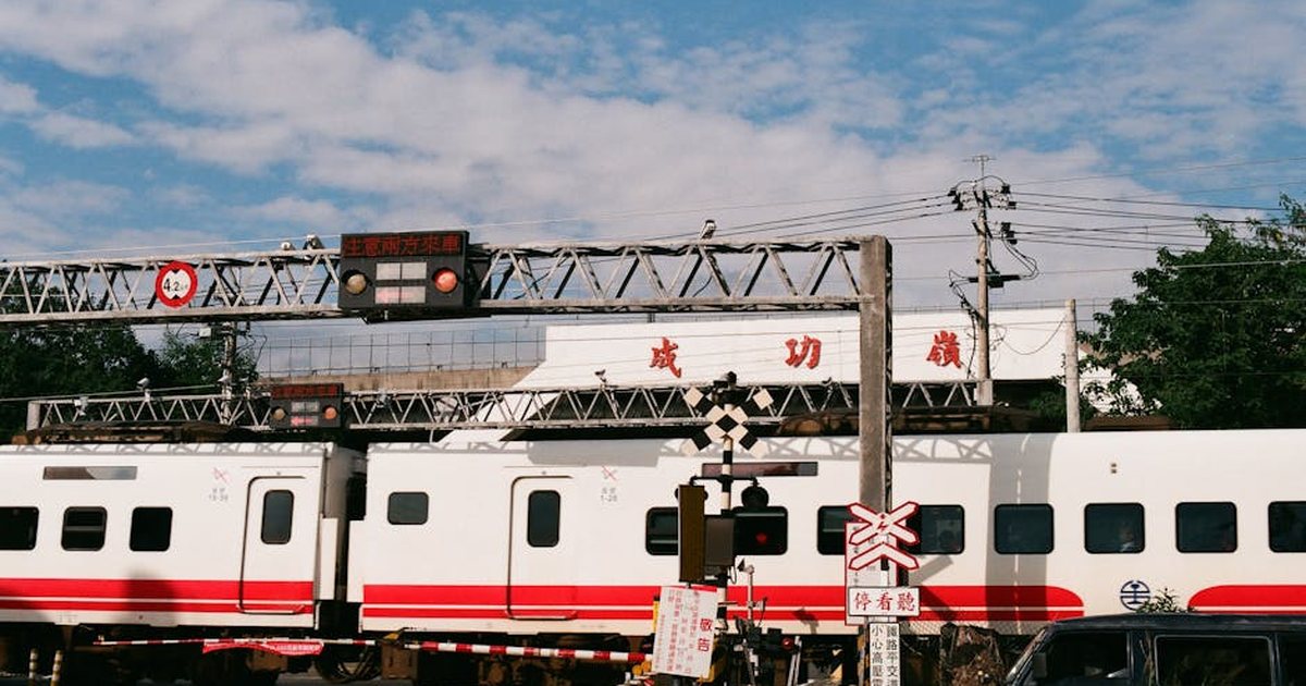 A train crosses an intersection in Taiwan with clear blue skies and signage.