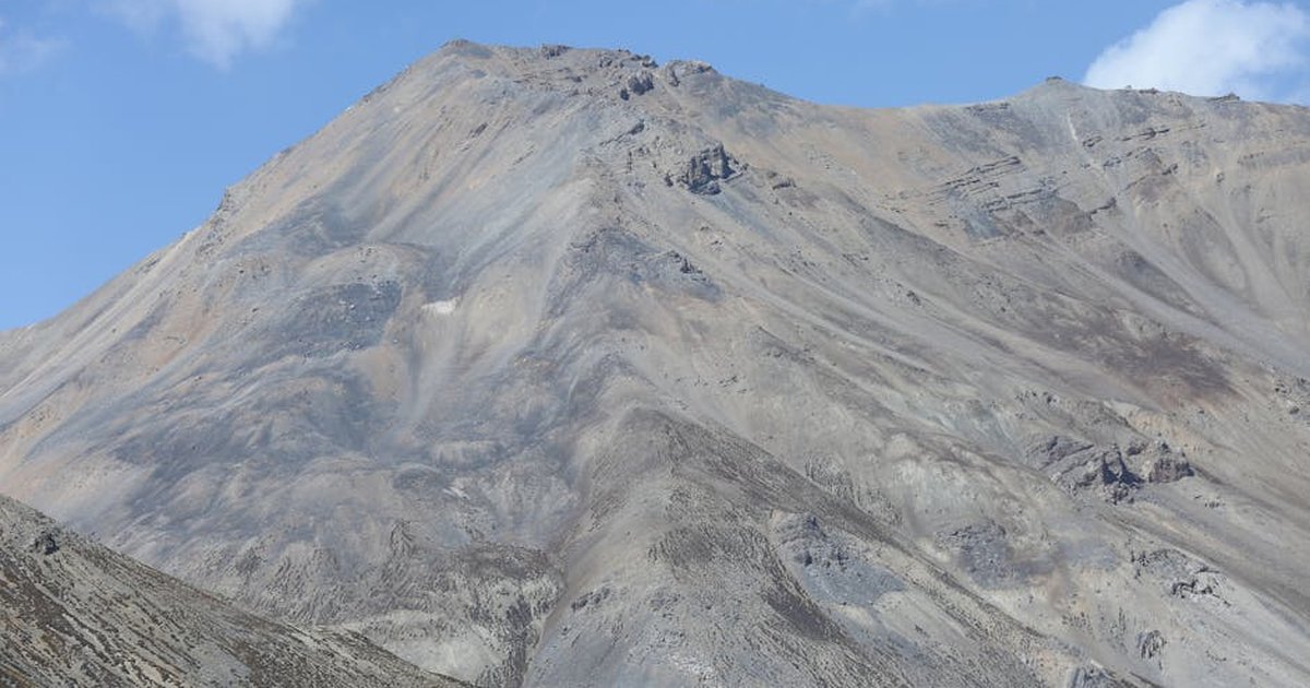 High mountain peak with rocky terrains under a clear blue sky, perfect for adventure enthusiasts.