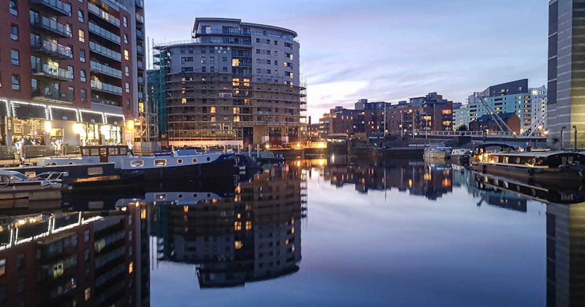 Evening view of Leeds Docks with reflections of modern apartments and calm waters.