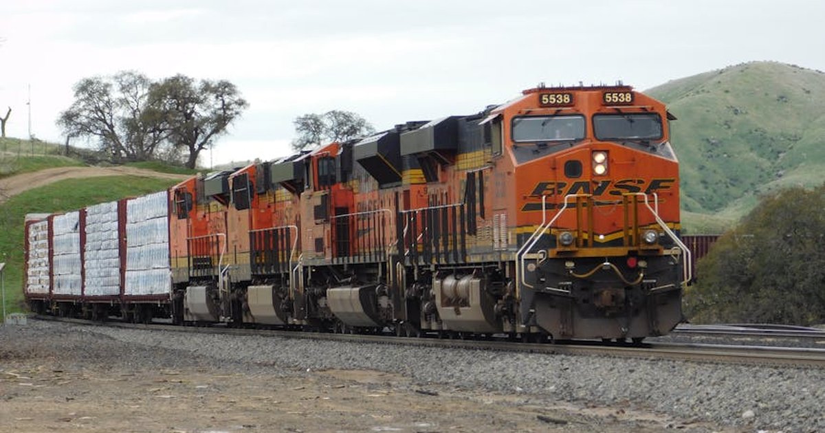 BNSF freight train transporting goods through a rural landscape on a clear day.